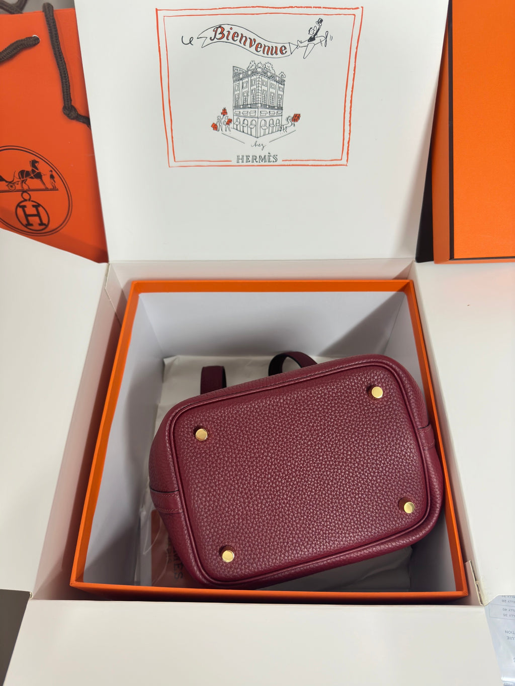 Burgundy textured leather mini bag with gold-tone studs and magnetic-style top