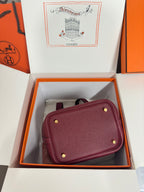 Burgundy textured leather mini bag with gold-tone studs and magnetic-style top