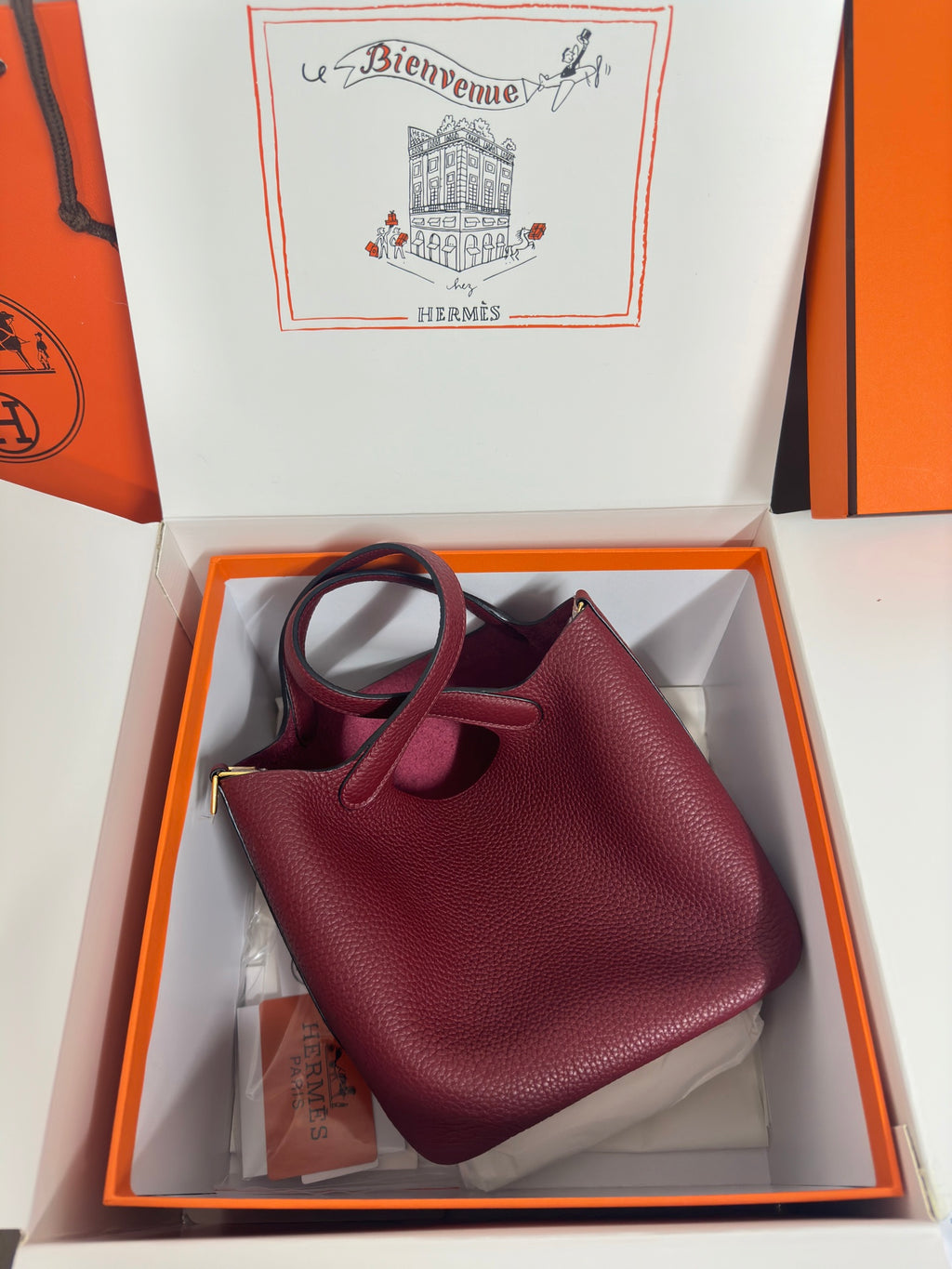 Burgundy textured leather tote bag with top handles and gold-tone clasp