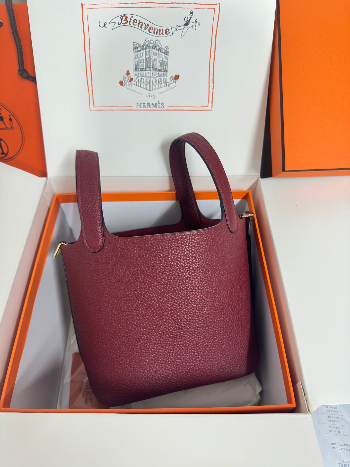 Burgundy textured leather mini tote with top handles and structured rounded shape