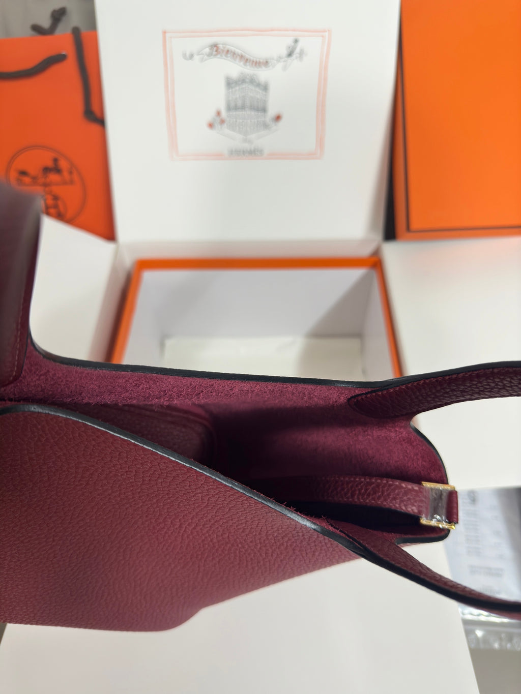 Burgundy textured leather tote strap with gold-tone buckle and fabric lining