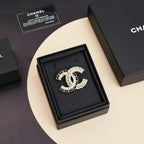 Gold-tone crystal brooch with interlocking C motif, displayed on black cushion