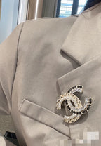 Gold-tone crystal brooch with interlocking C, pearl accents and dark stones on fabric