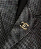 Gold-tone interlocking C brooch with crystal and pearl details on grey blazer lapel