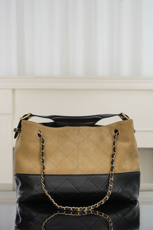 Tan and black quilted shoulder bag with chain handles and gold-tone logo detail