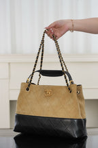 Tan and black quilted bag with chain handles and gold-tone logo, side view