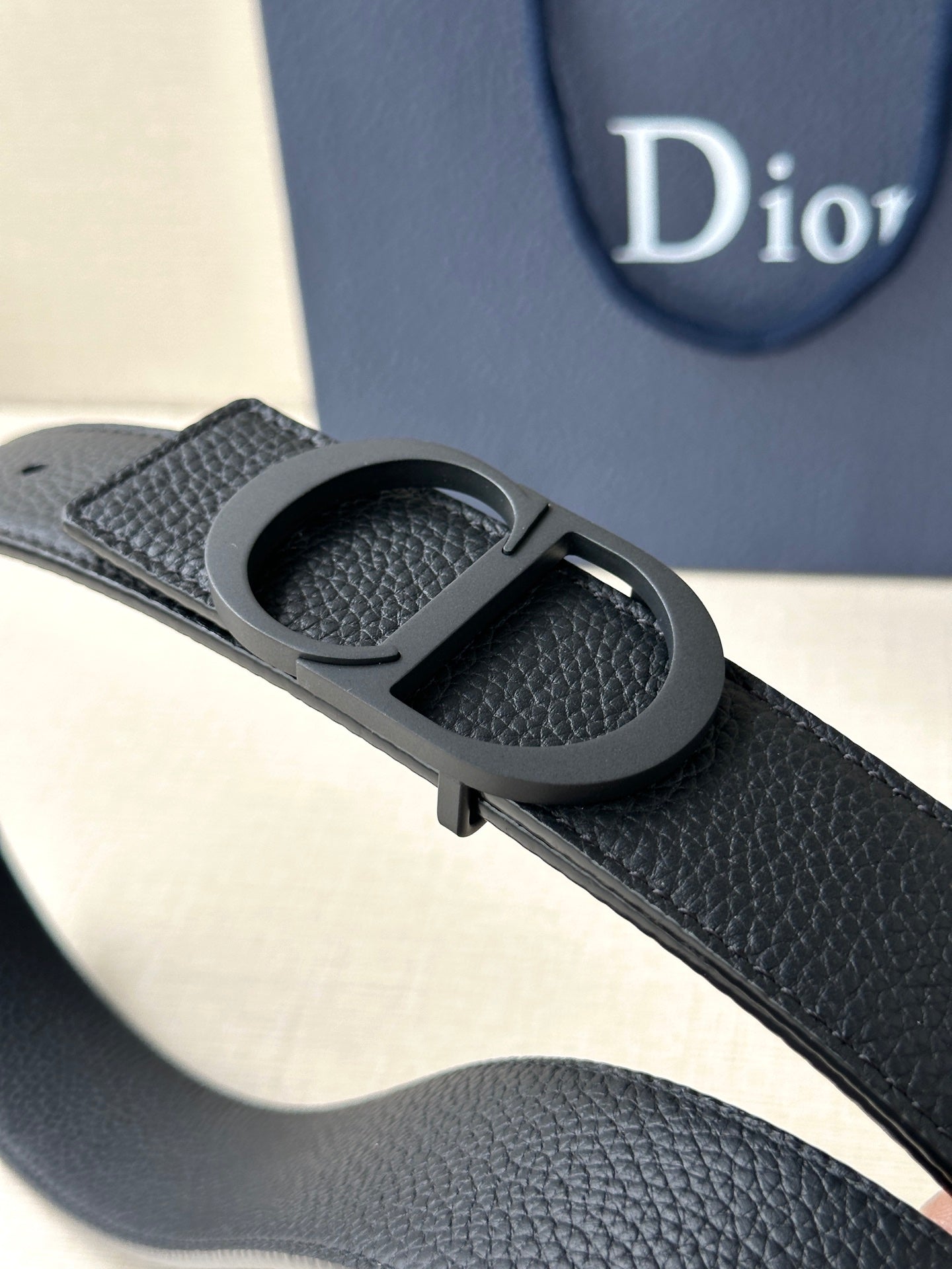 Black textured leather belt with CD buckle close-up