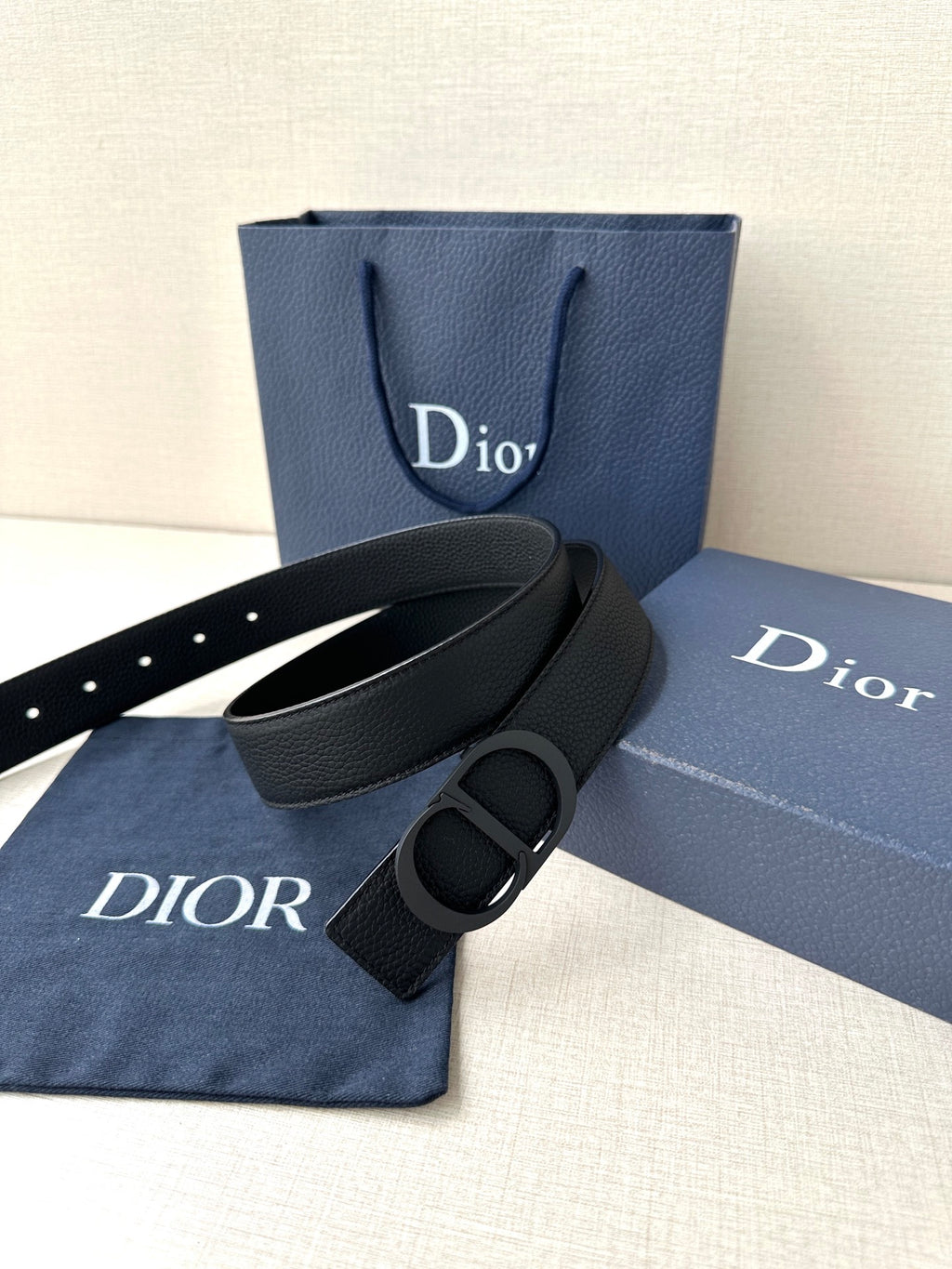 Black leather Dior belt with CD buckle, shown with matching dust bag