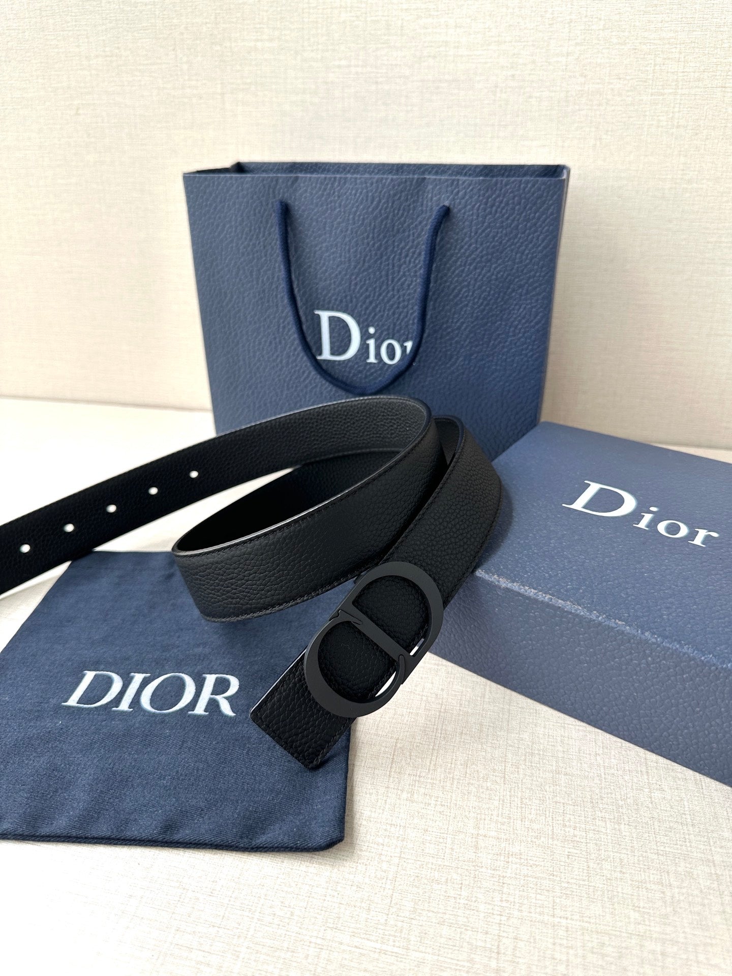 Black leather Dior belt with CD buckle, shown with matching dust bag
