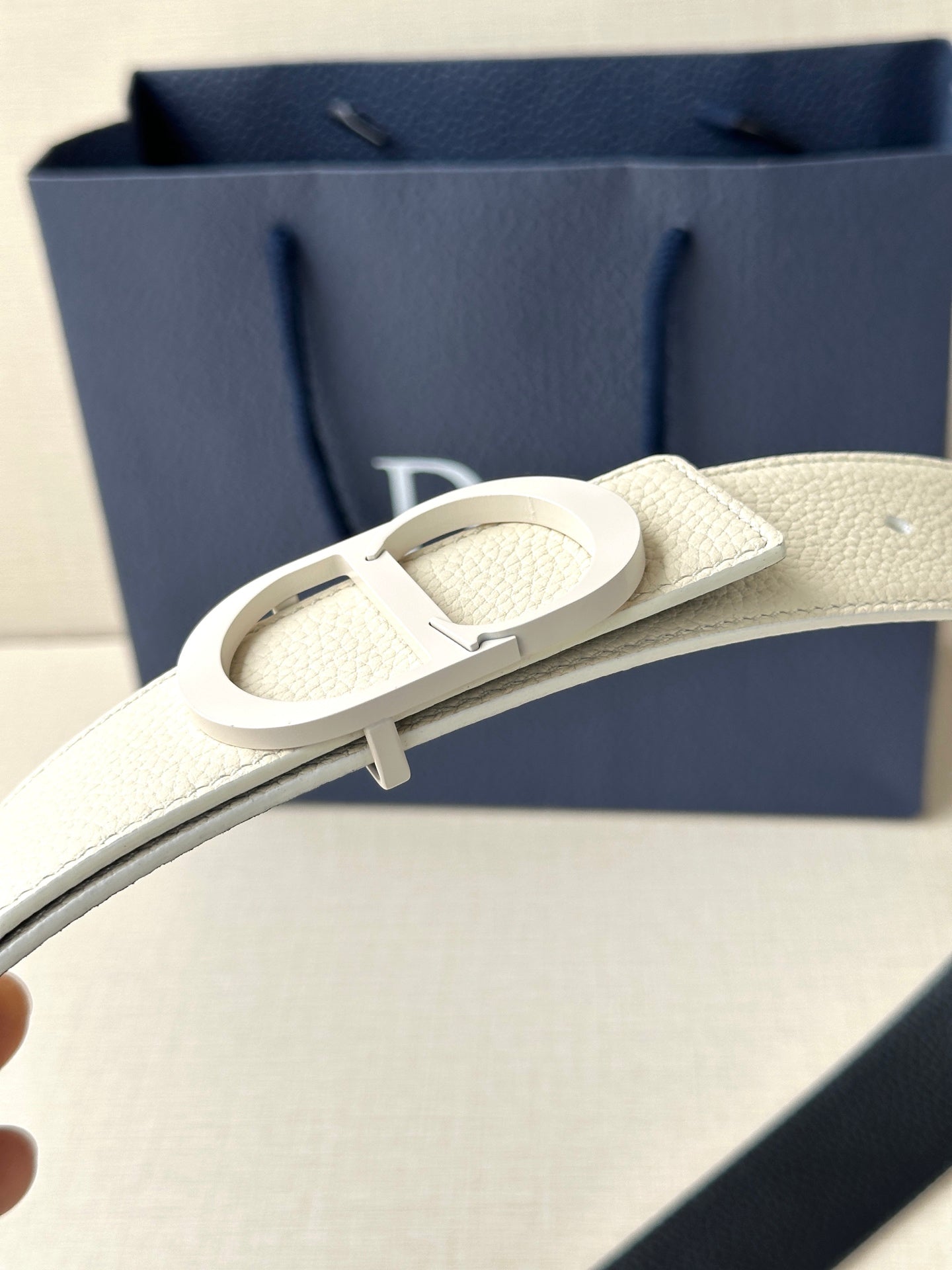 Beige leather belt close-up with silver-toned buckle and embossed Dior logo