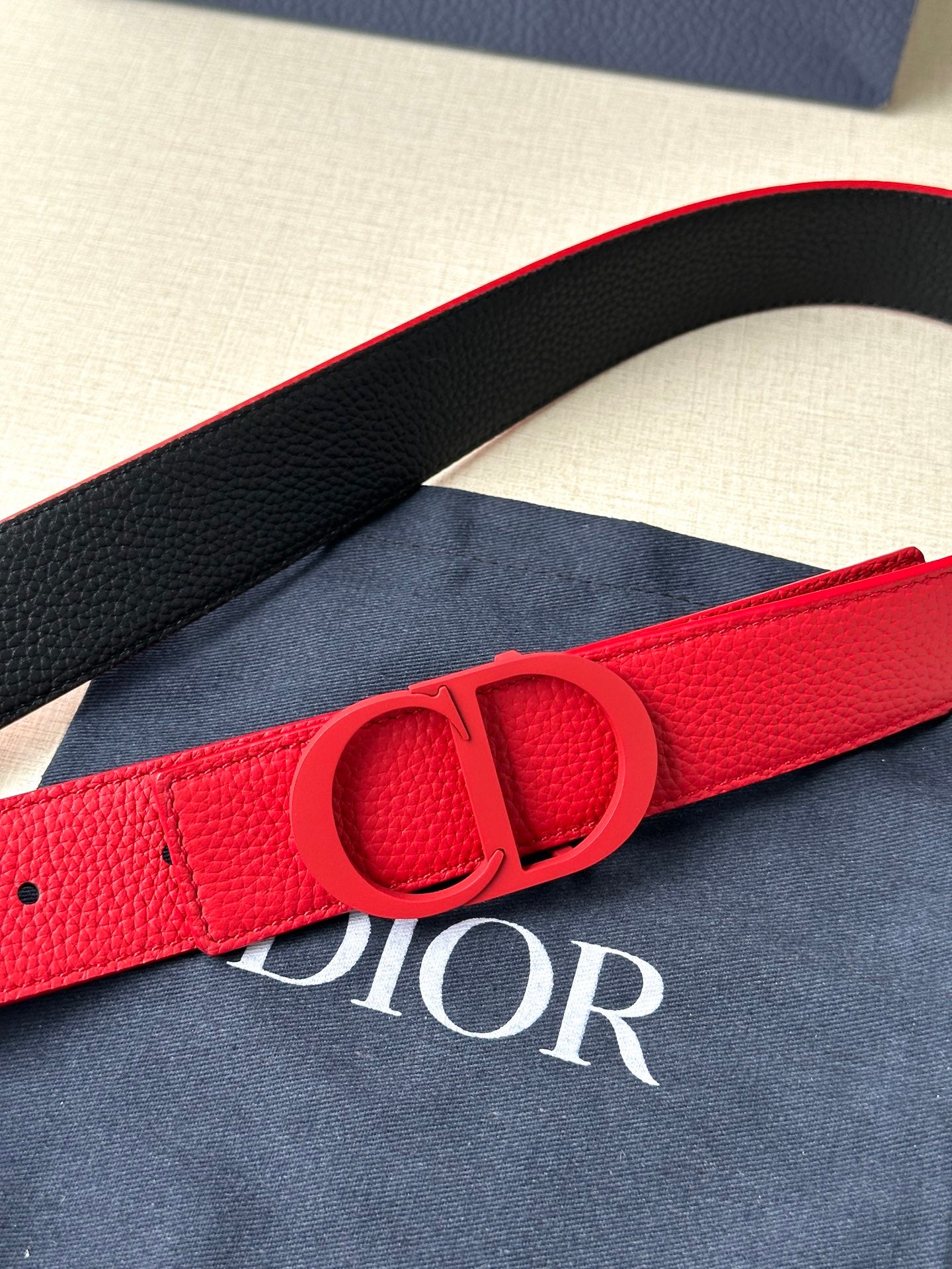 Red leather Dior belt with embossed Dior buckle close-up