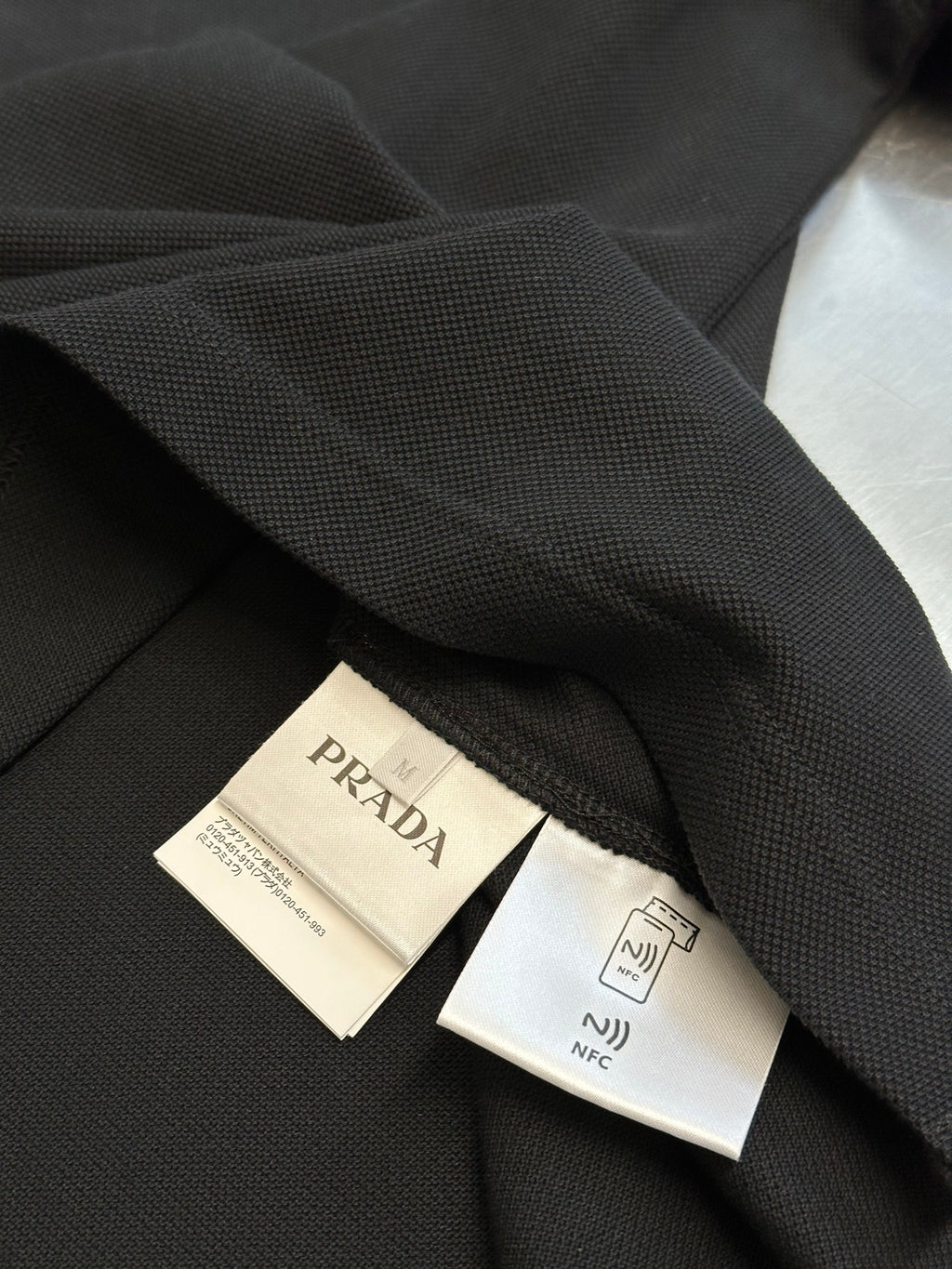 Prada polo shirt tags and label on dark fabric