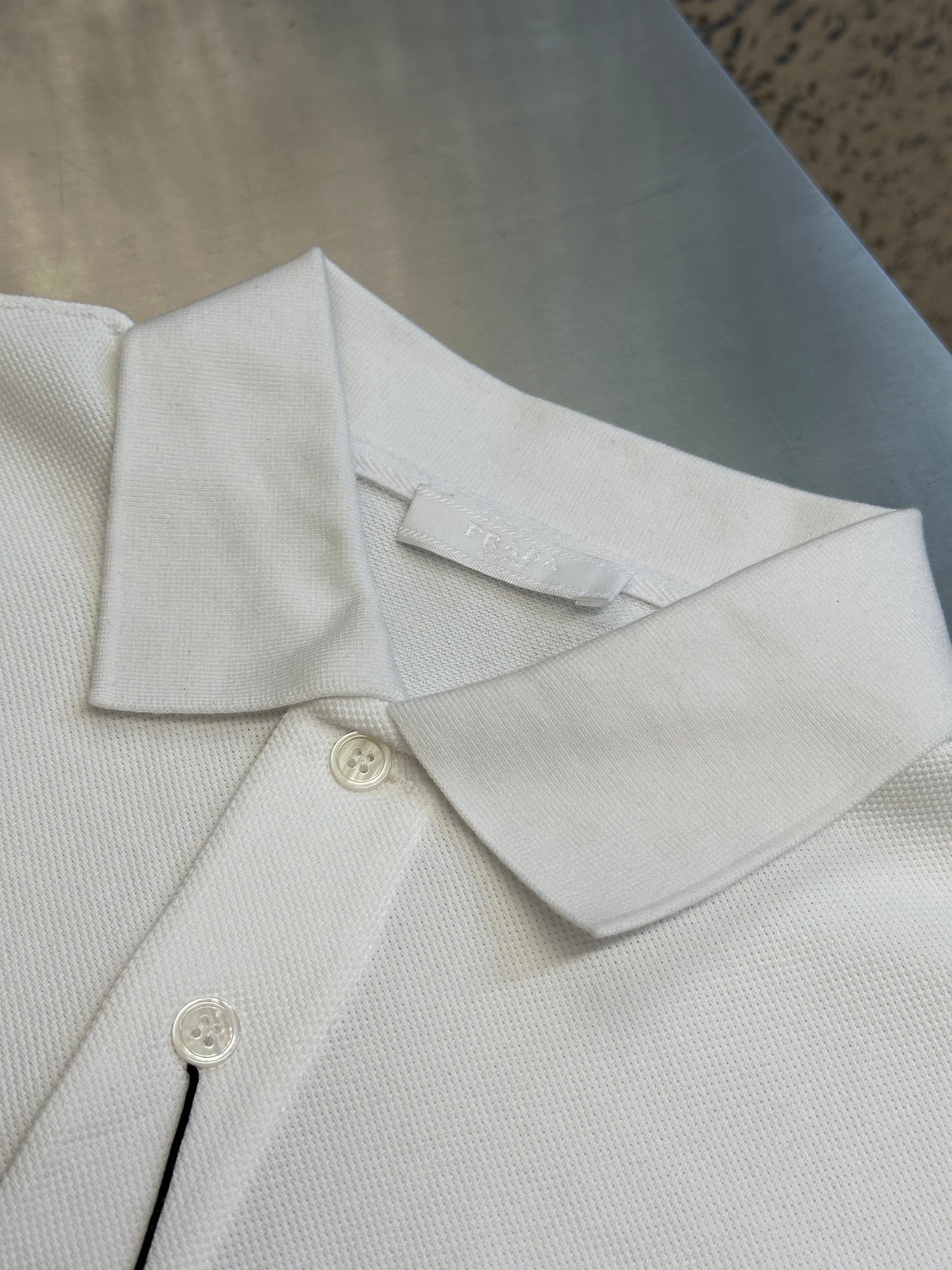 White polo shirt collar and button placket with fabric texture and small logo