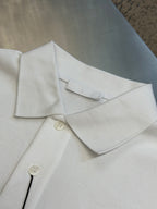 White Prada polo shirt collar and button placket with visible stitching and tags.