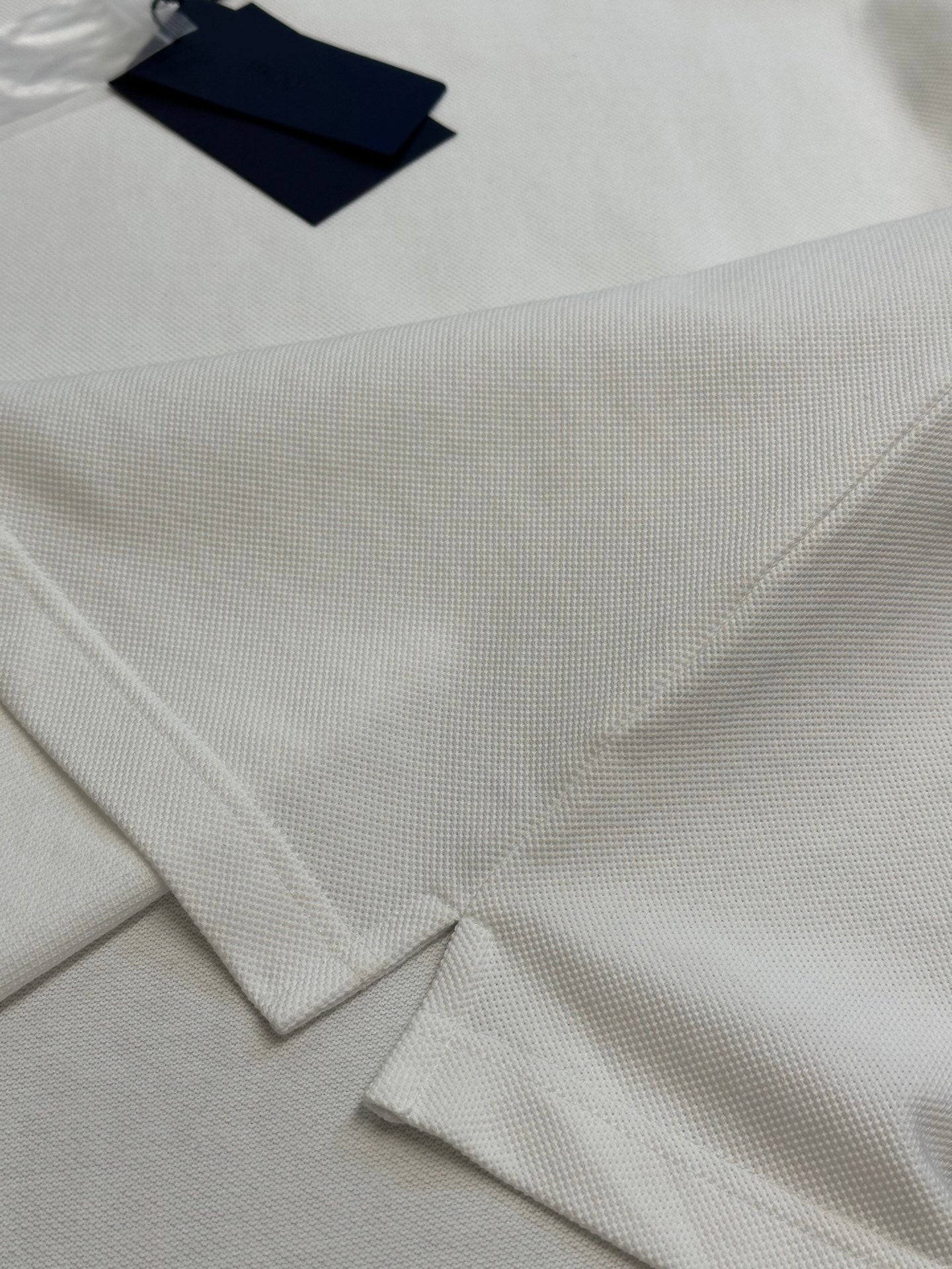 White polo shirt fabric close-up with folded collar and placket stitching