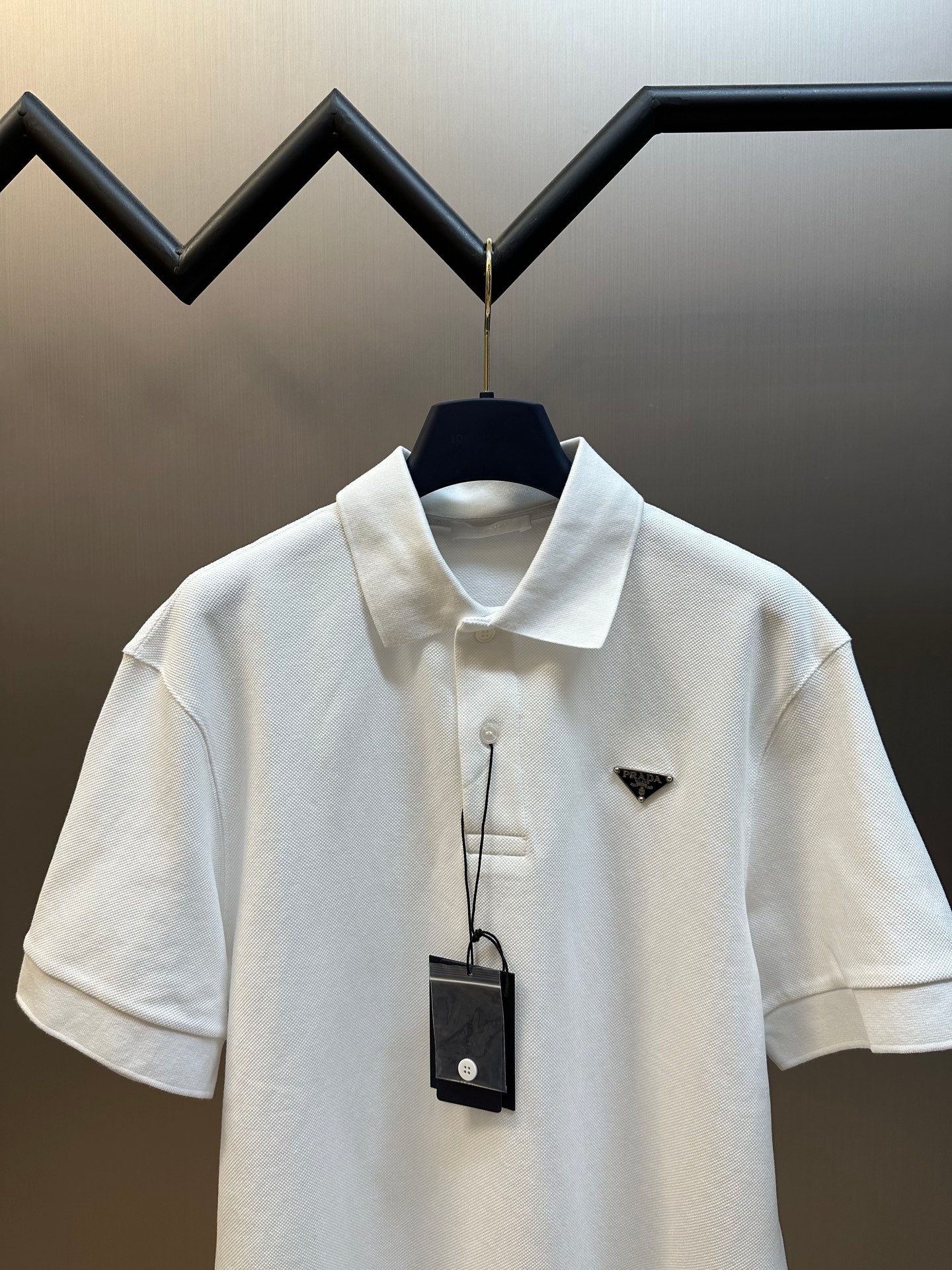 White polo shirt on hanger with short sleeves, collar, and small triangular logo
