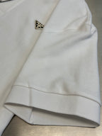 White polo shirt sleeve cuff with small triangular logo badge