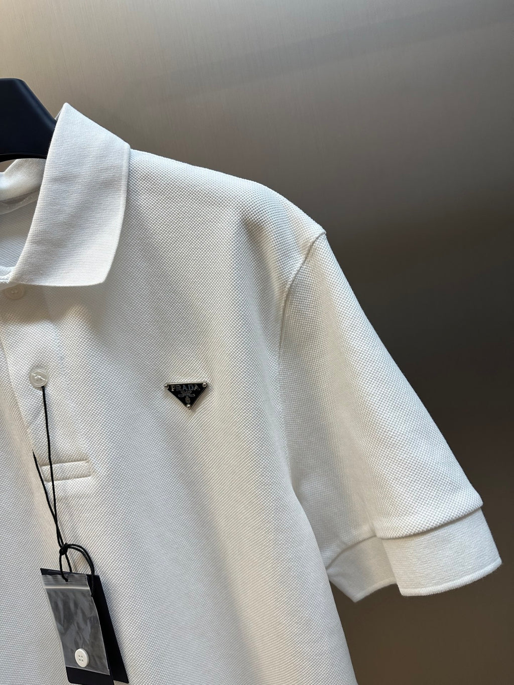 White polo shirt close-up of short sleeve and triangular logo badge on chest