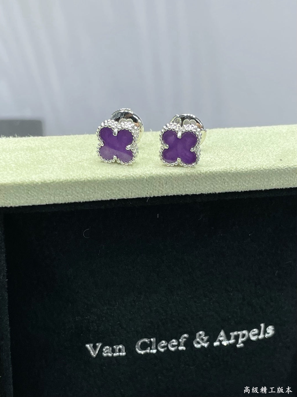 Purple clover stud earrings resting on Van Cleef & Arpels case