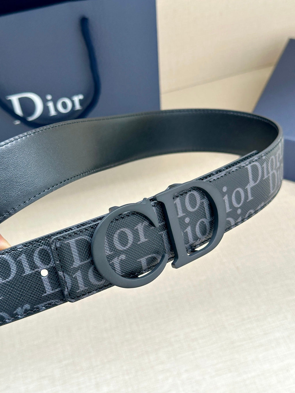 Dark blue monogram belt with large round logo buckle and adjustable strap