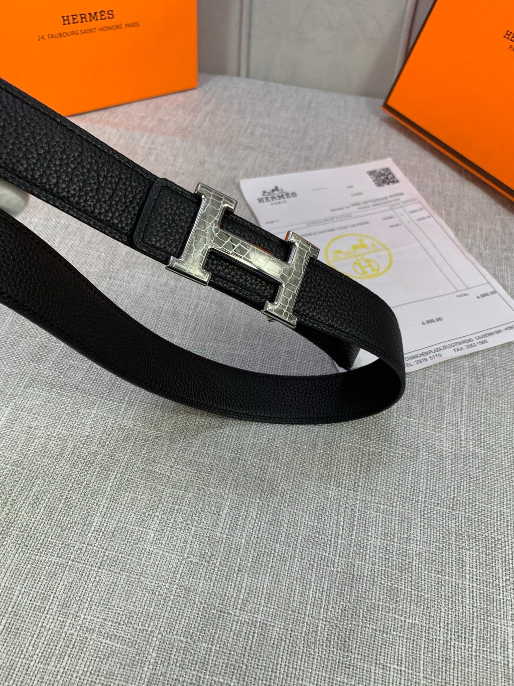 Black textured leather belt lying flat with silver-tone buckle