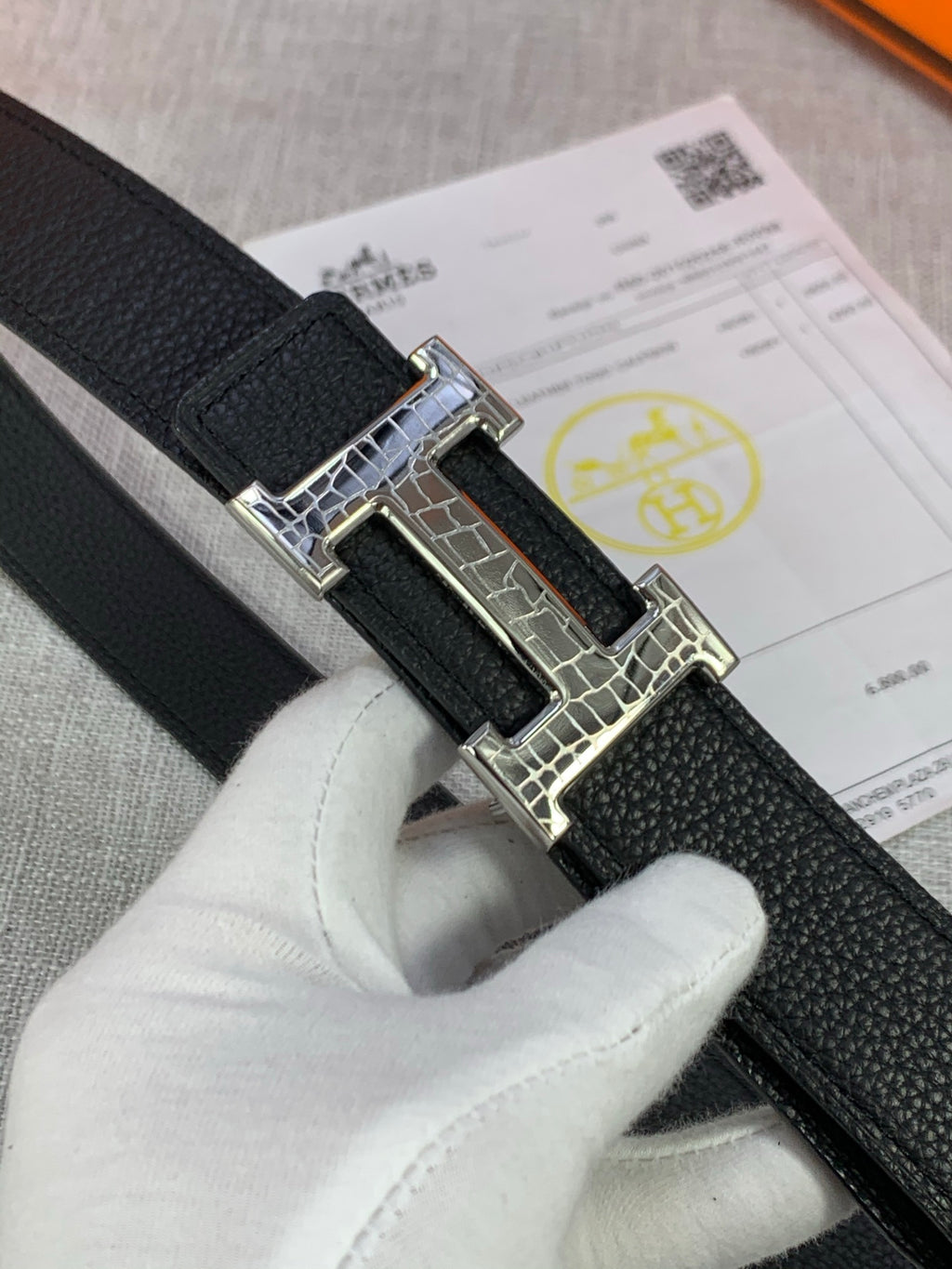 Black textured leather belt with silver-tone buckle detail and keeper