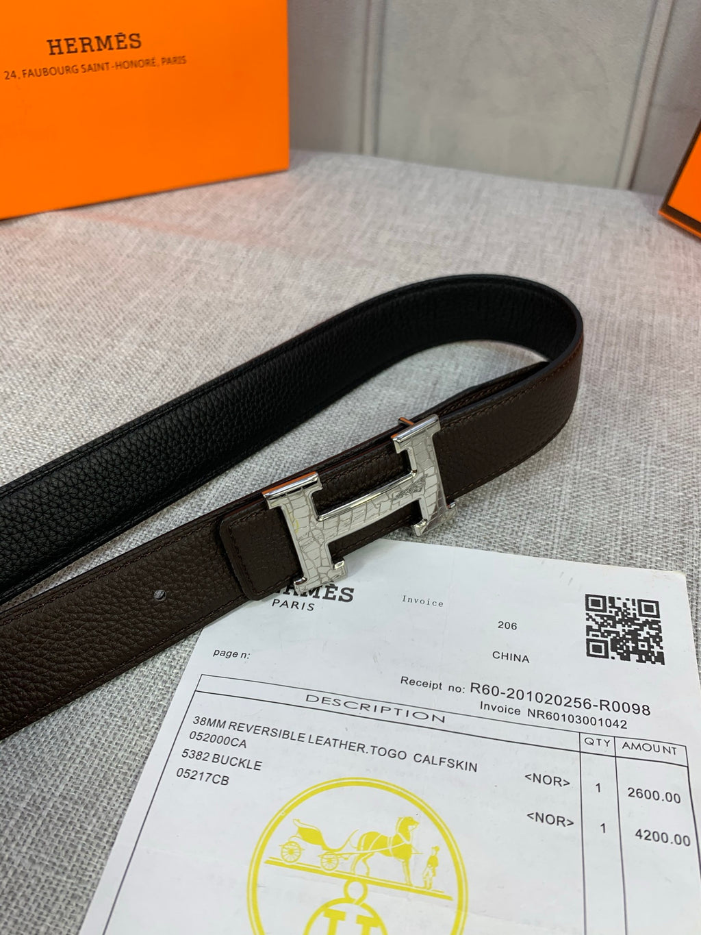 Leather belt with dark brown strap and silver H buckle, side view on holder