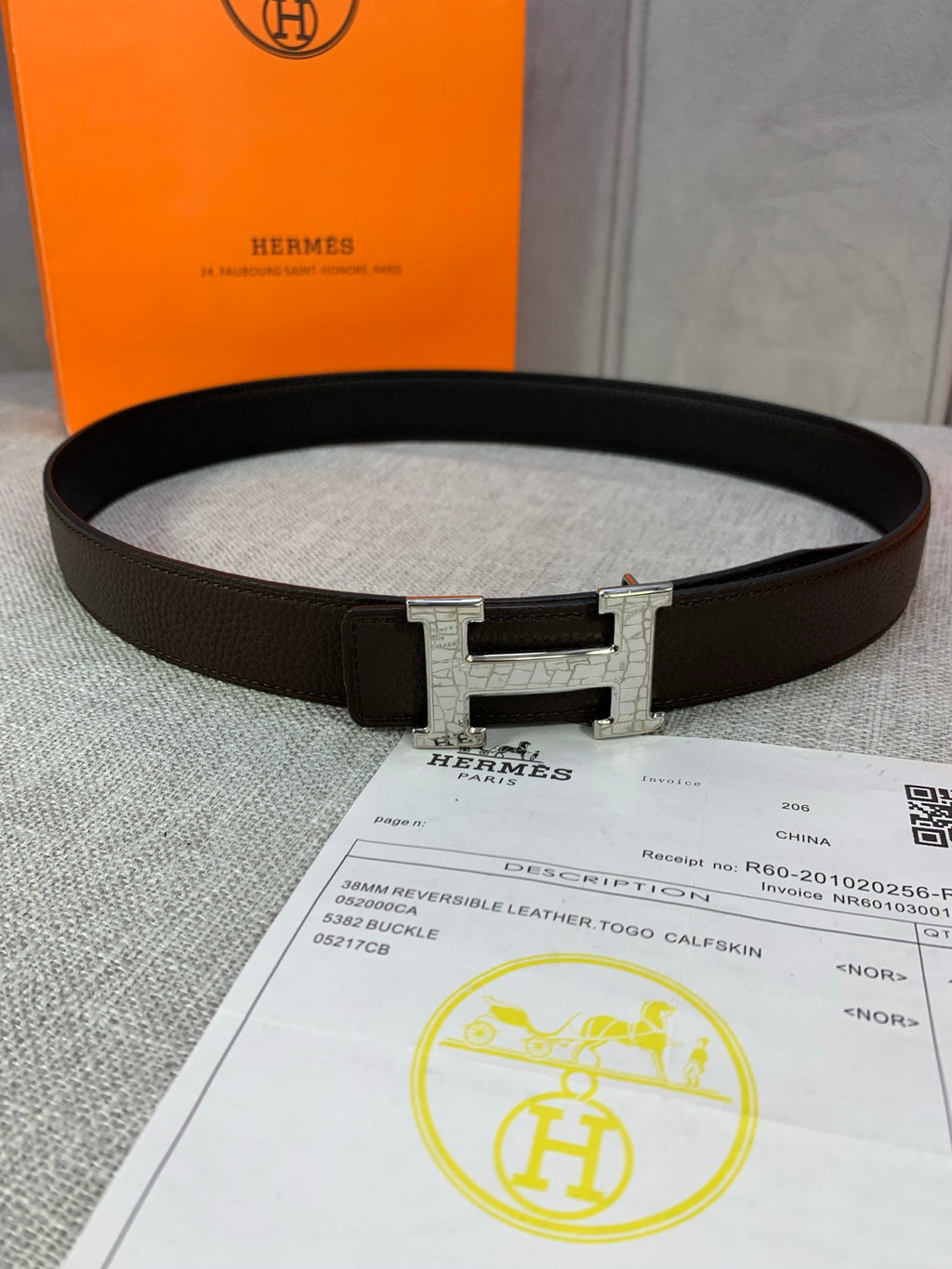 Leather belt with dark brown strap and silver H buckle, centered on surface