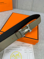 Reversible leather belt: olive outer strap and black underside with silver square buckle.