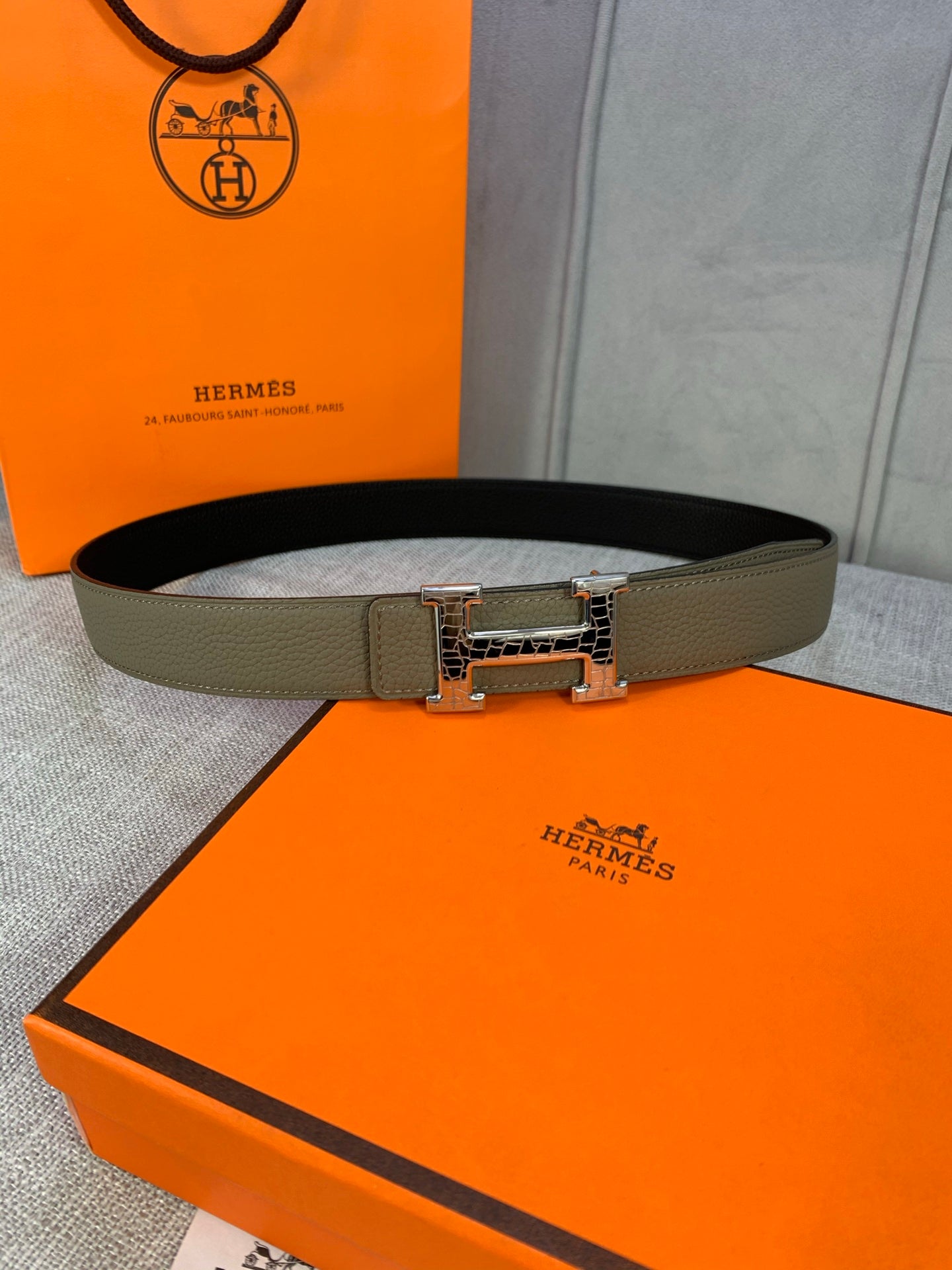 Olive leather belt with silver-toned square buckle, laid flat.