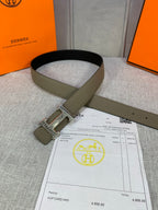 Olive leather belt looped on display with silver square buckle and strap holes.