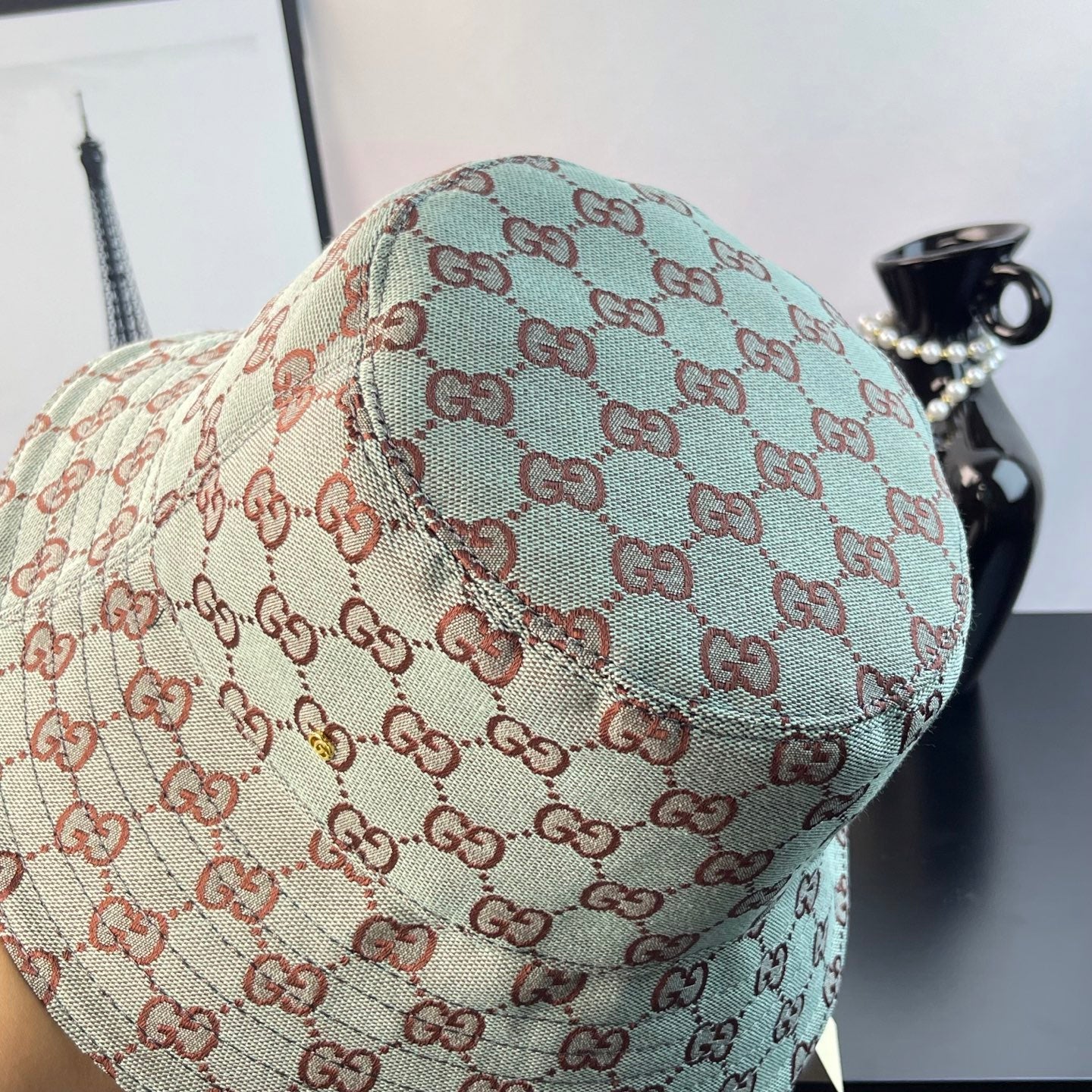 Bucket cap side view with GG monogram print in teal and cream with red-brown