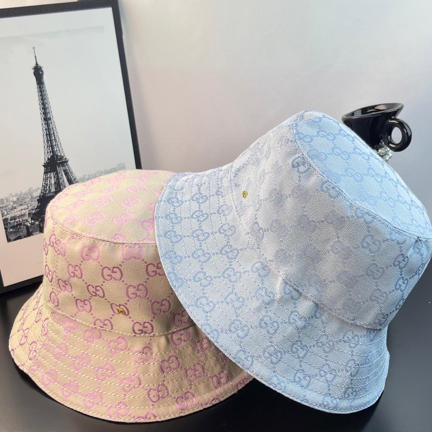 Two monogram bucket hats: pink and light blue GG patterns with curved brims