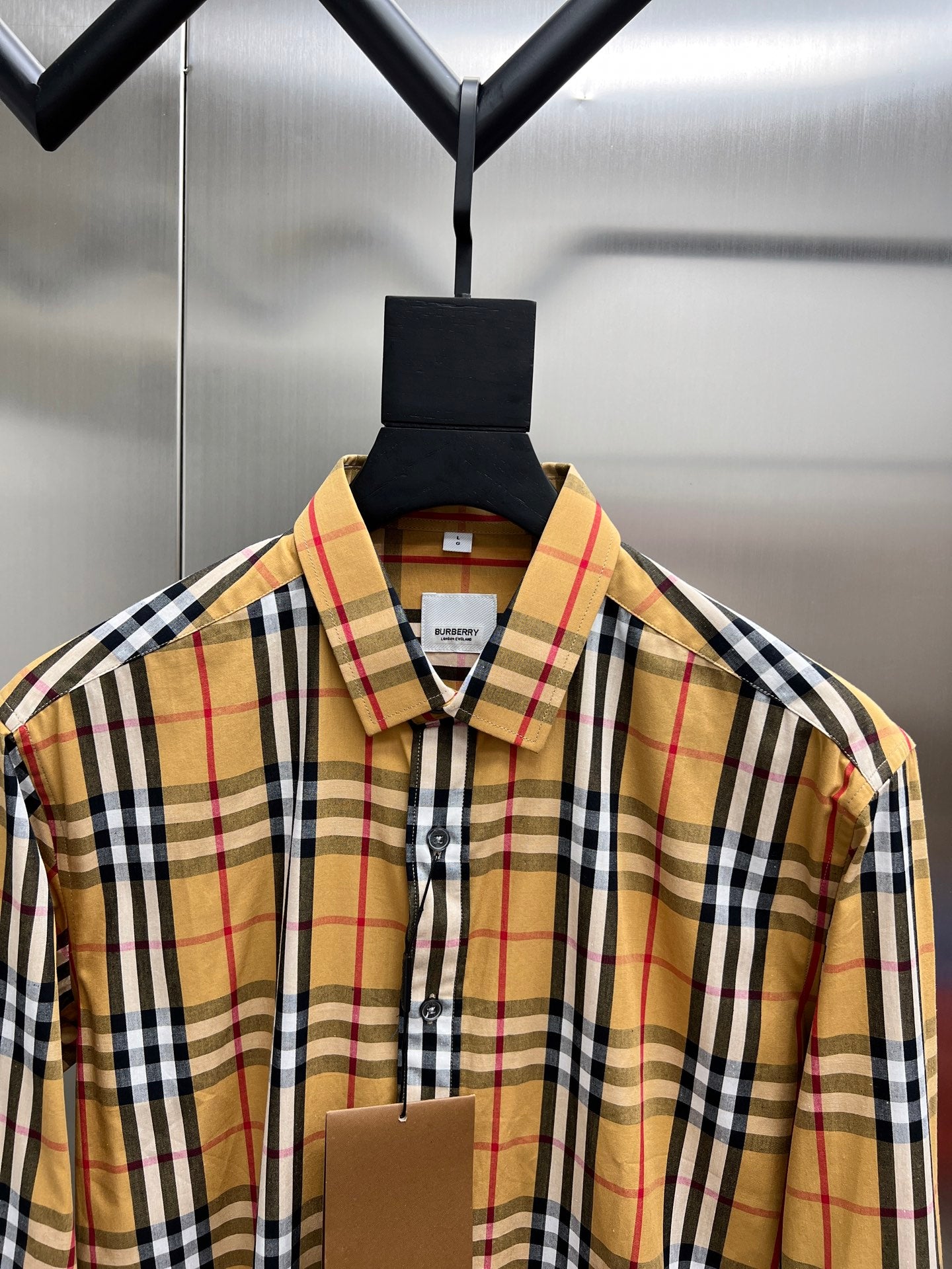 Plaid button-up shirt collar with front buttons and brand label at chest