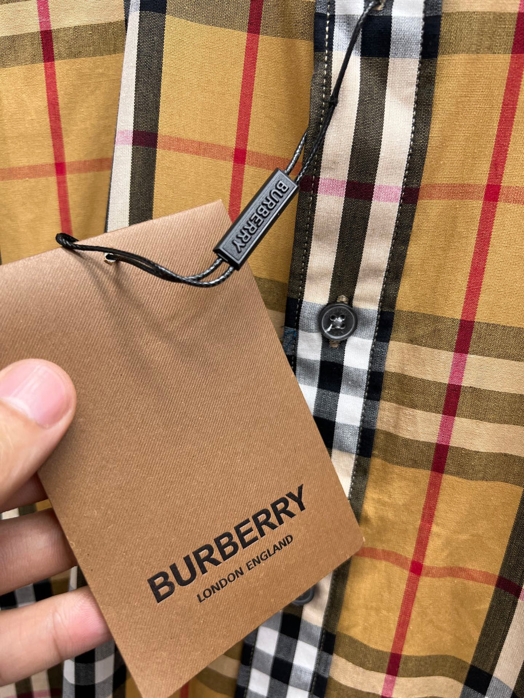 Plaid shirt with attached hang tag reading BURBERRY LONDON ENGLAND