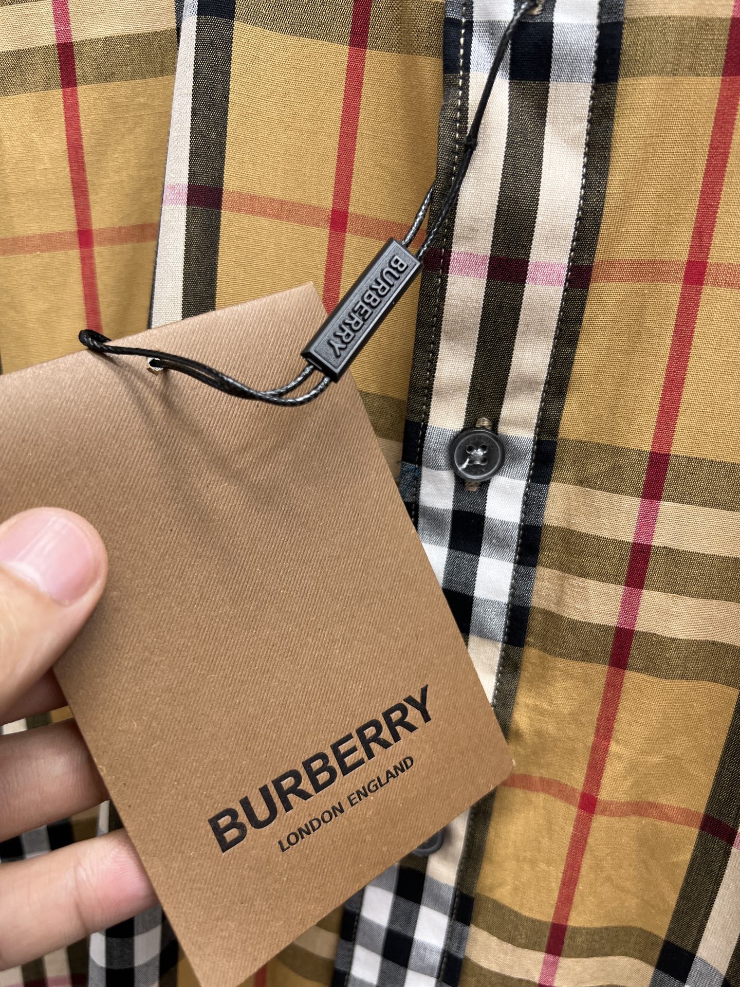 Plaid shirt with attached hang tag reading BURBERRY LONDON ENGLAND