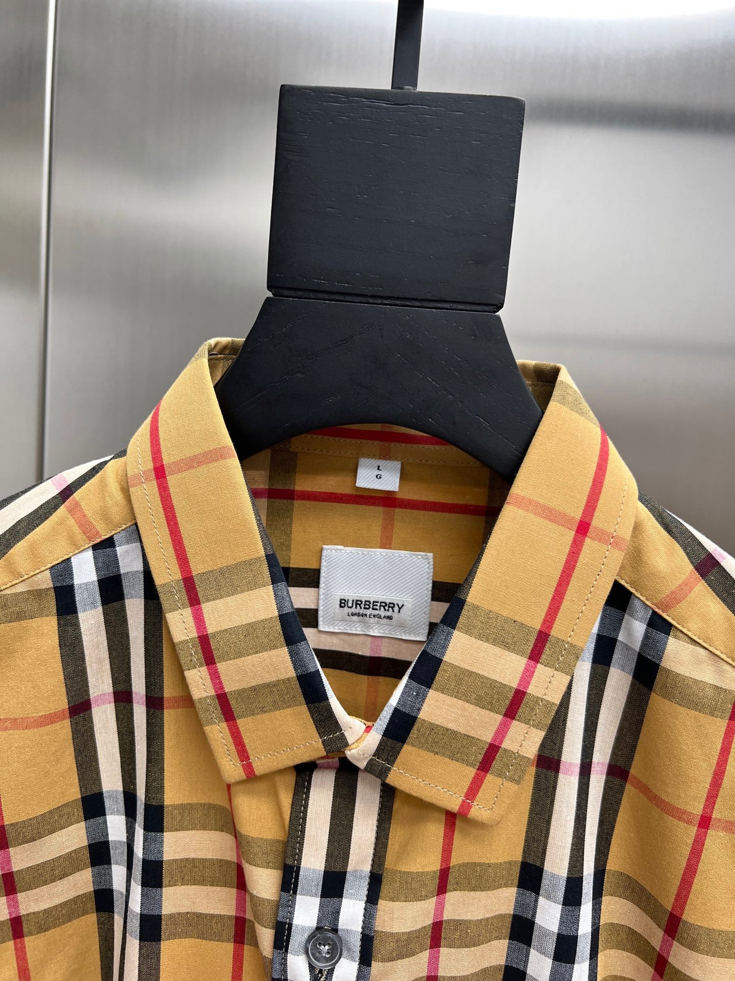 Plaid button-up shirt with collar and chest logo patch