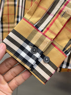 Plaid shirt cuff with button detail and visible stitching at hem