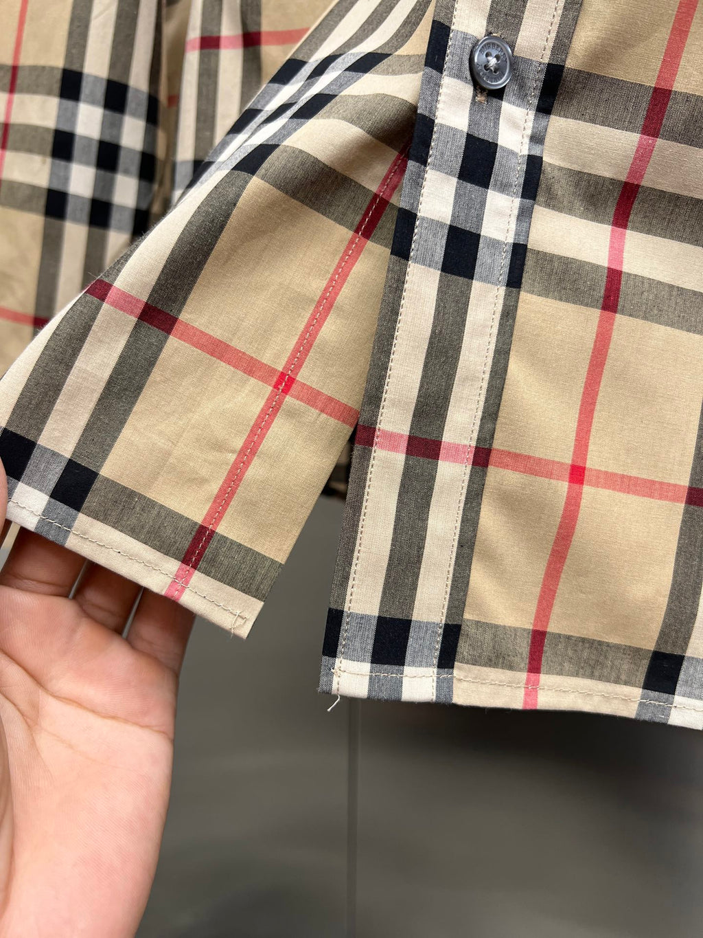 Burberry plaid shirt sleeve cuff with button, close-up on fabric stitching
