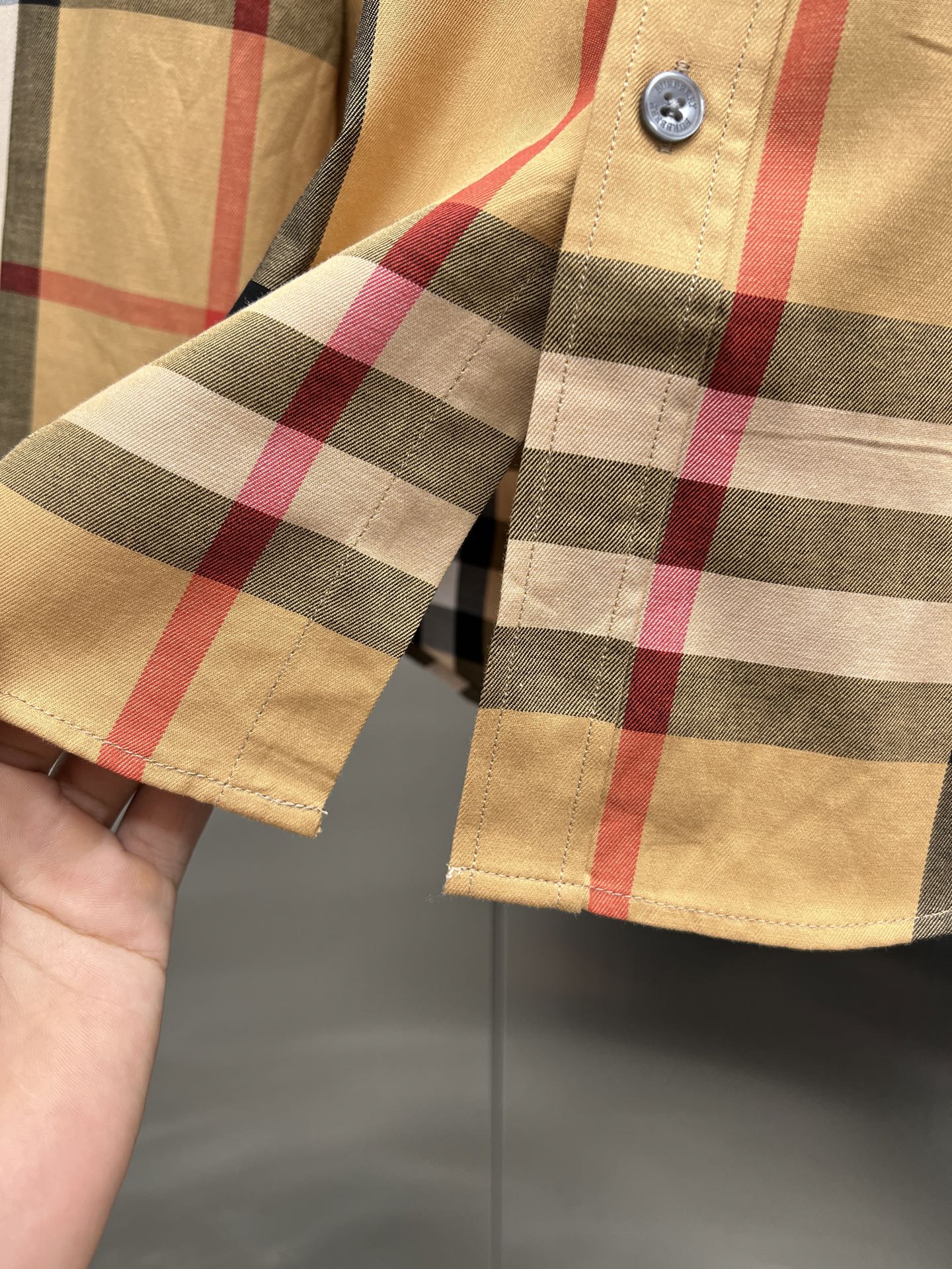 Burberry check shirt sleeve cuff close-up with button fastening