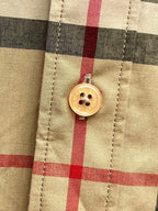 Burberry plaid shirt button detail close-up, round gold button on tan and black checks