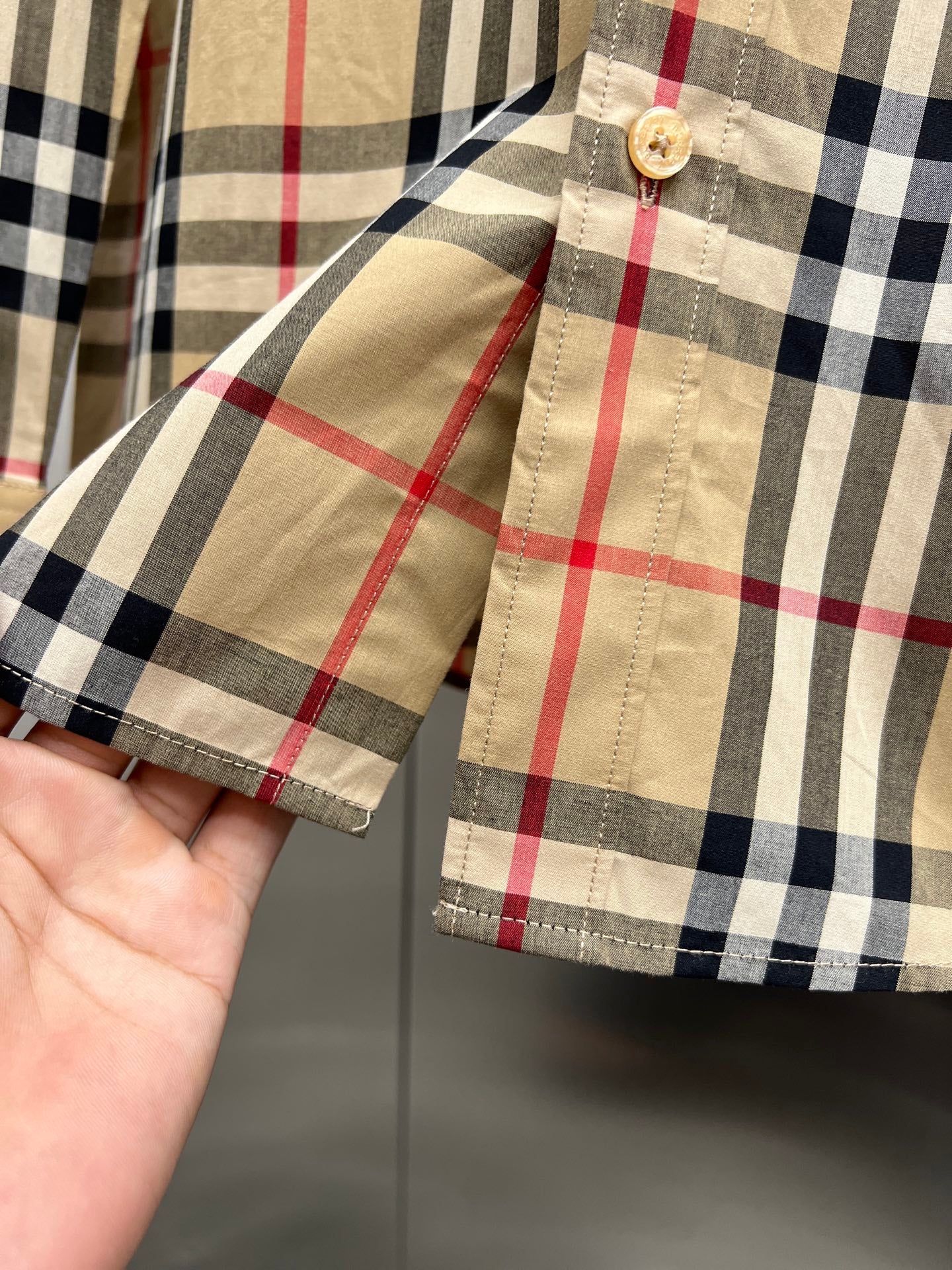 Burberry plaid shirt cuff and sleeve seam detail, tan with black and red checks