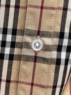 Placket button detail on a plaid shirt front with stitched seams