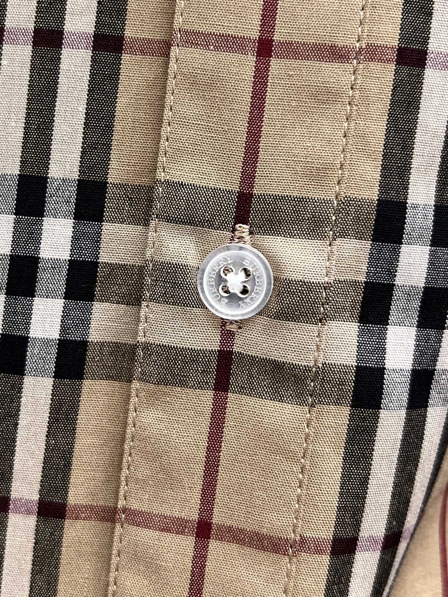 Placket button detail on a plaid shirt front with stitched seams