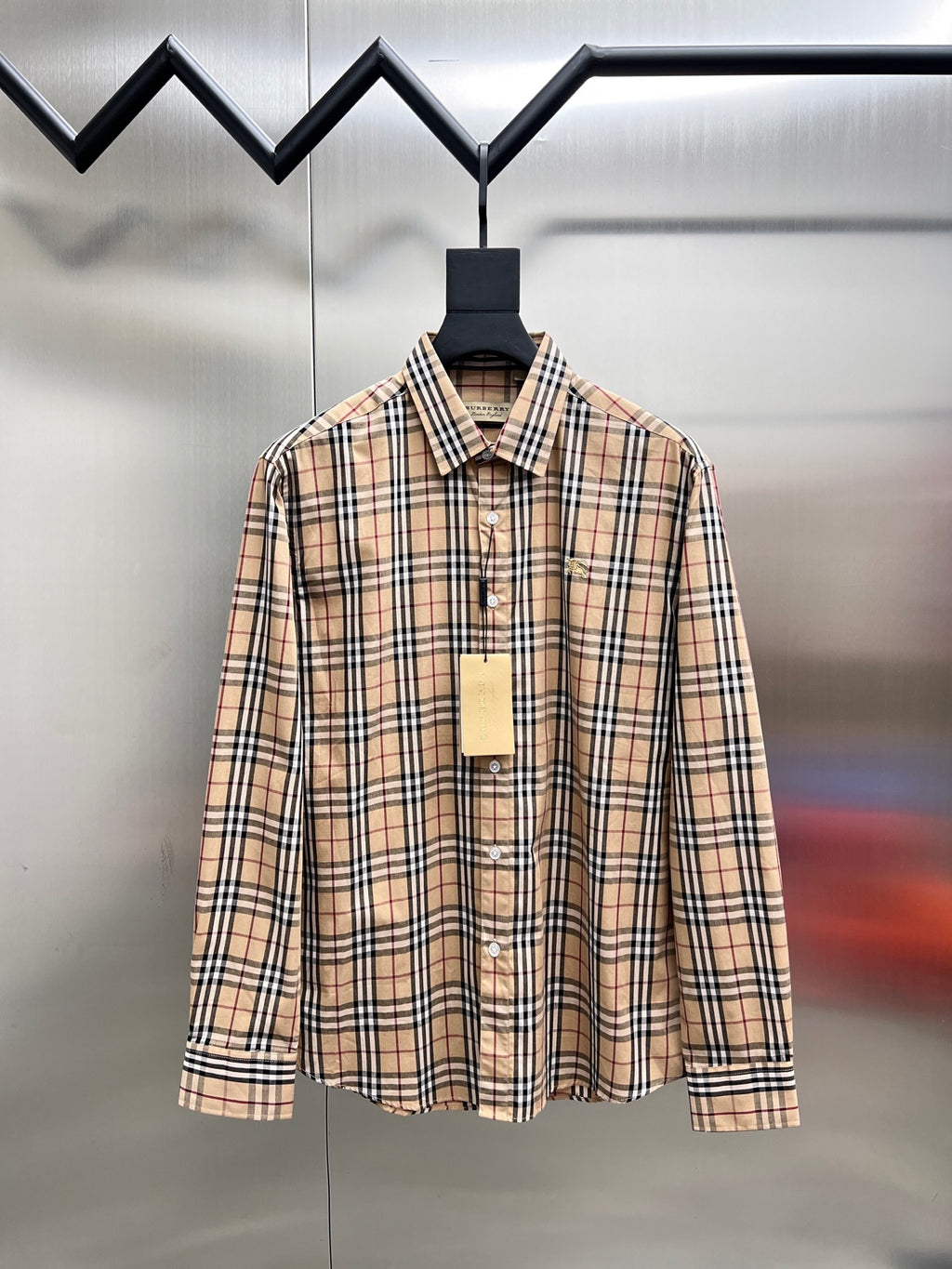 Plaid button-up shirt with long sleeves and front button placket, on a hanger