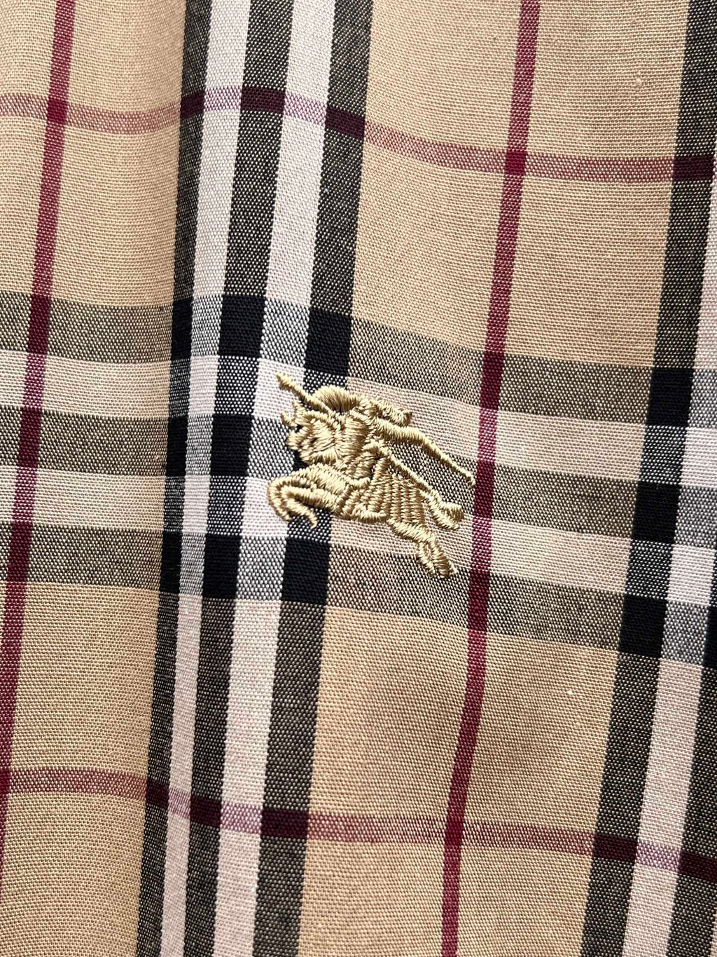 Plaid fabric swatch with embroidered crest logo at center
