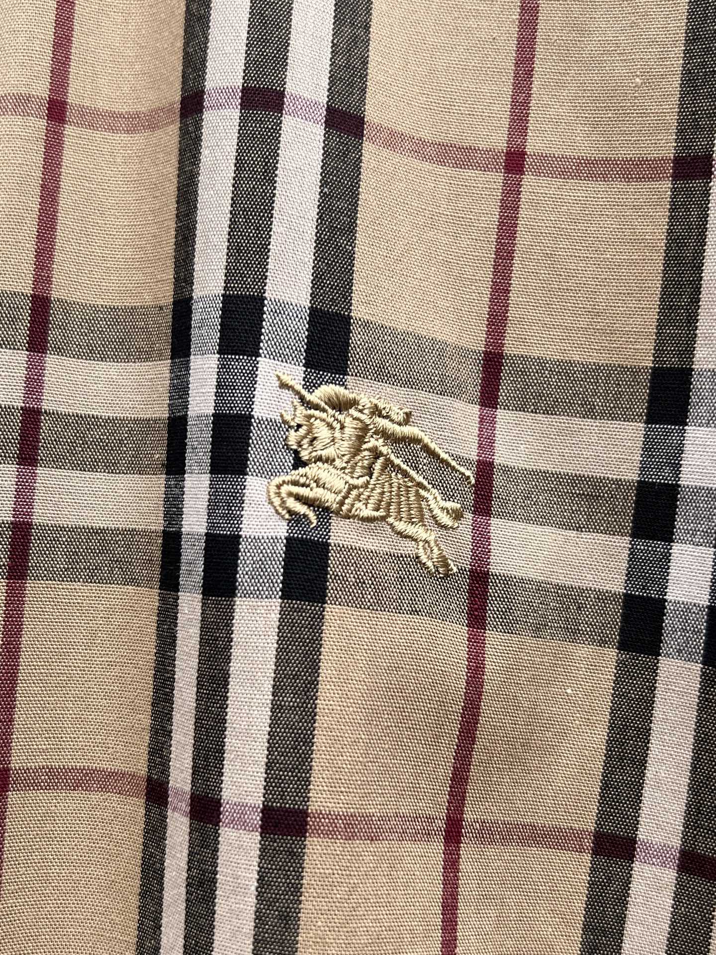 Plaid fabric swatch with embroidered crest logo at center