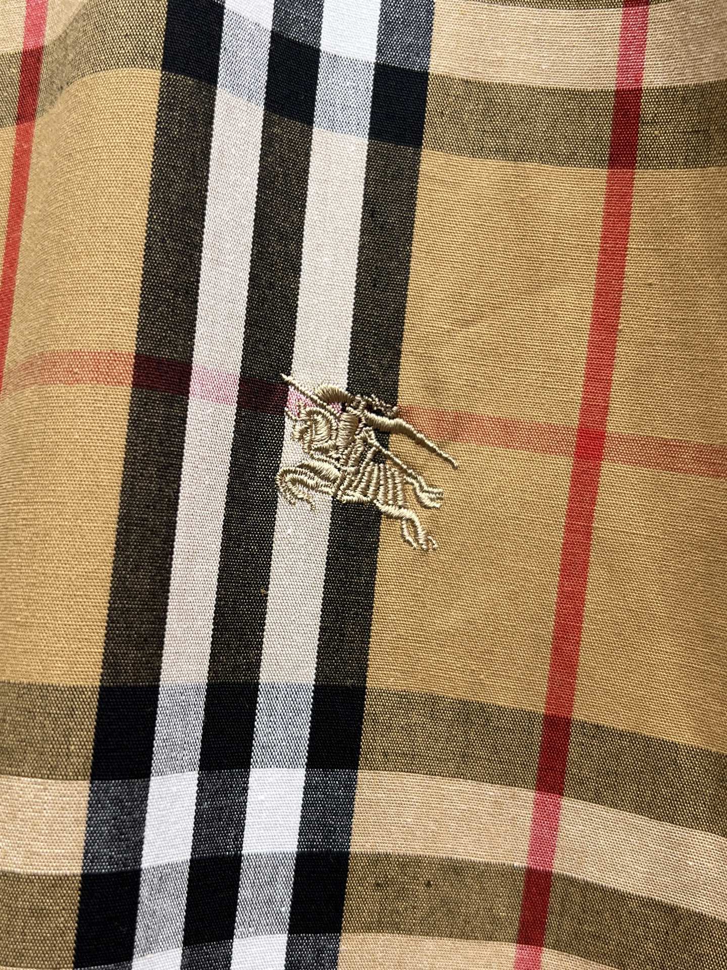 Plaid shirt fabric close-up with decorative embroidered strap detail on chest