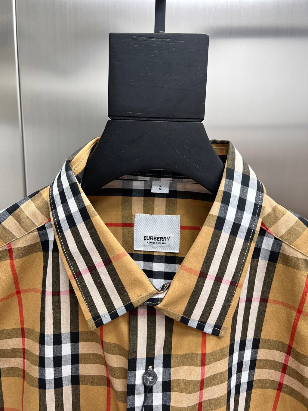 Plaid shirt collar close-up with brand label and buttoned neckline