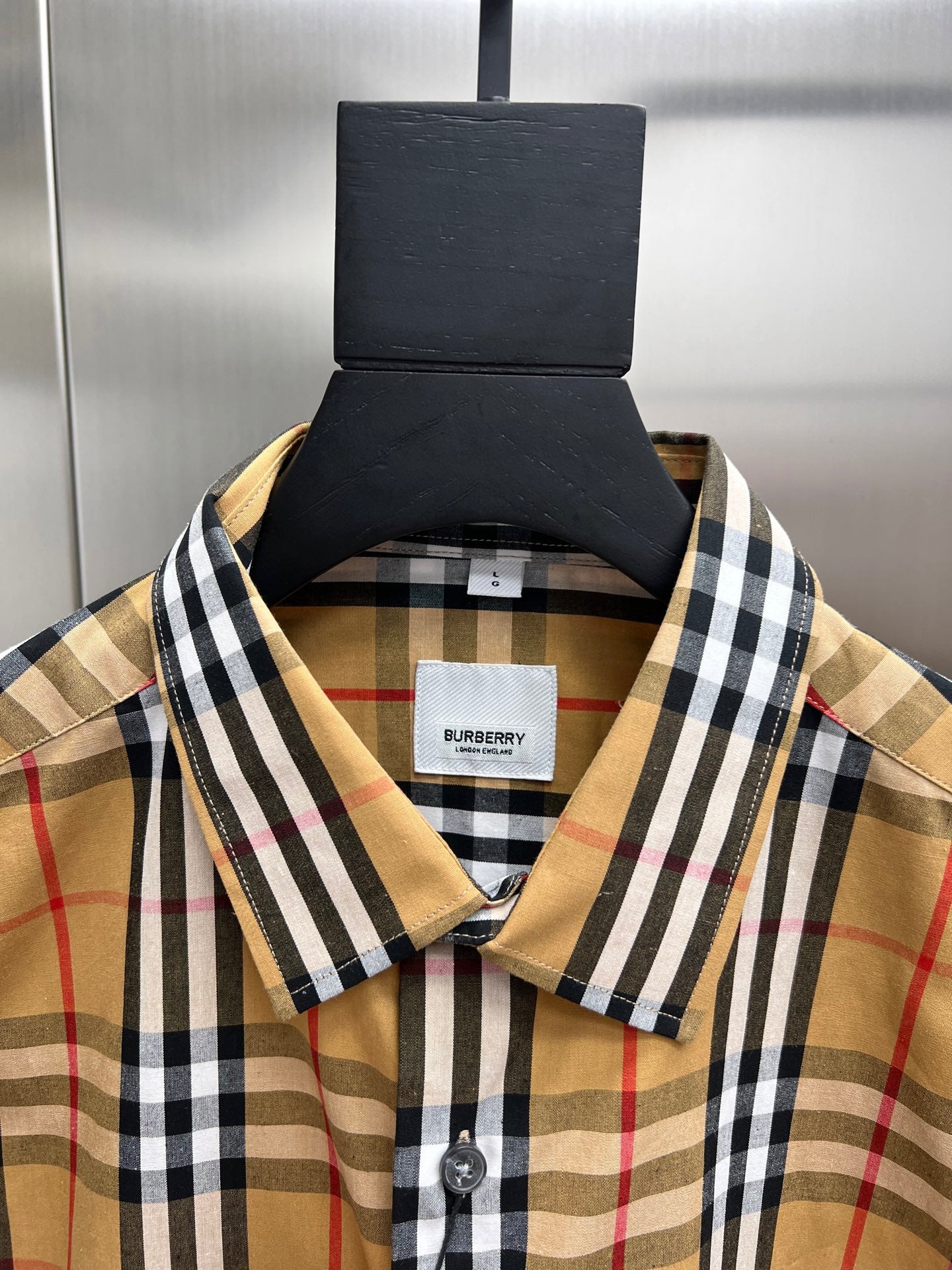 Plaid shirt collar close-up with brand label and buttoned neckline